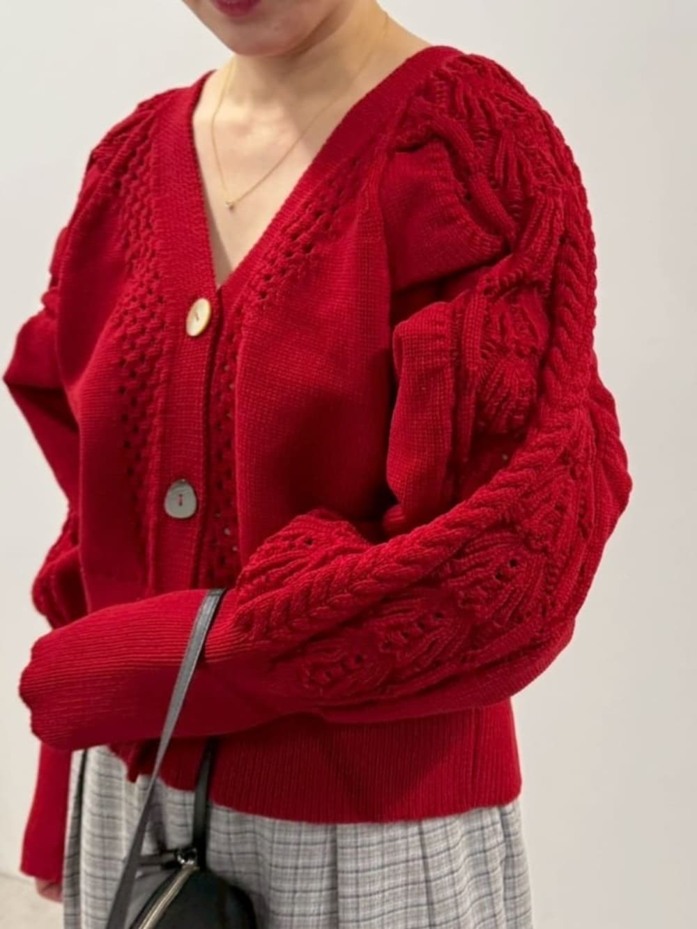 ブラック系のローファー、ブラック系のボストンバッグ、レッド系のカーディガン/ボレロを着用したレディースの冬コーディネートの5枚目の写真