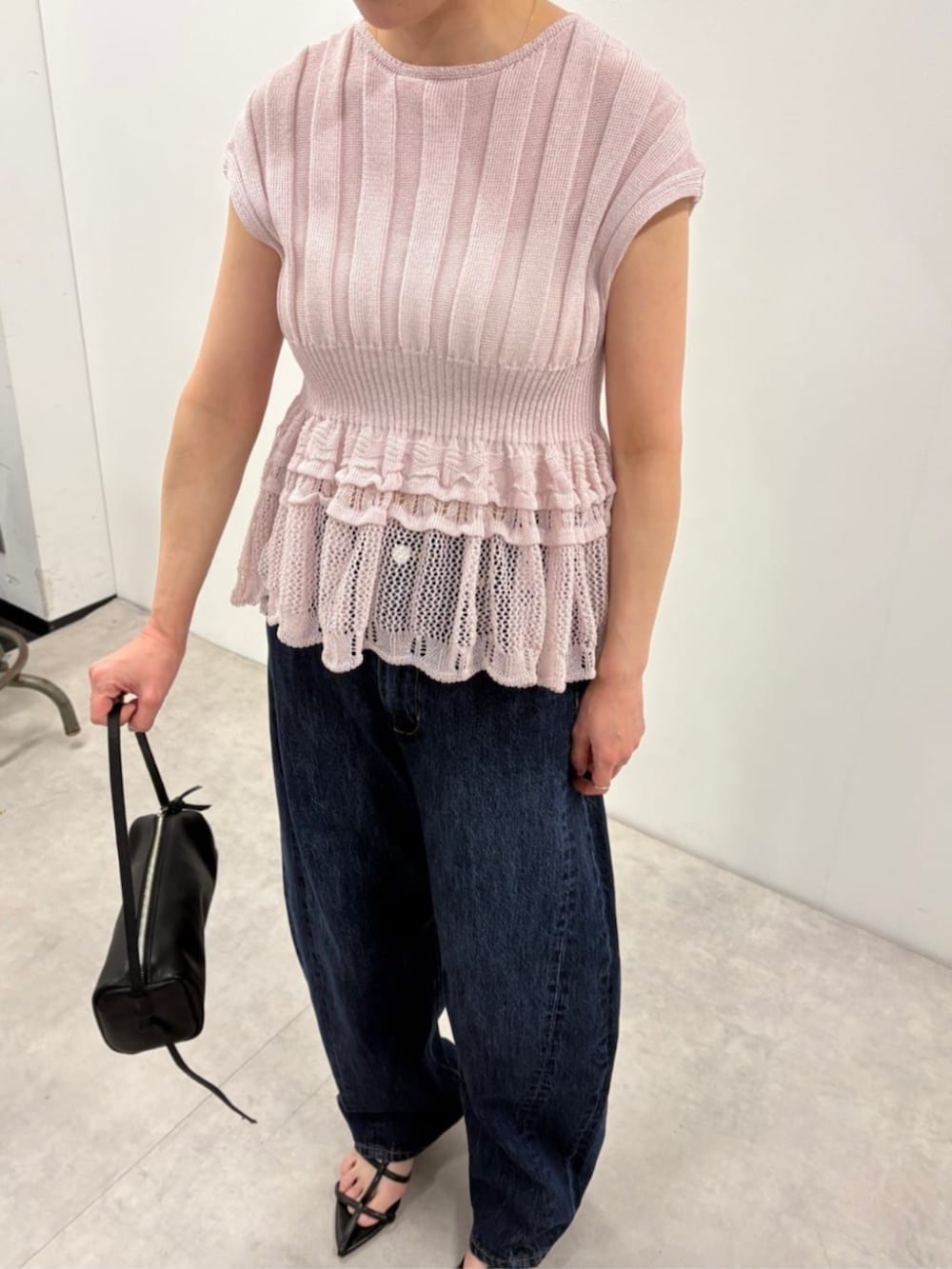 ブラック系のボストンバッグ、ブルー系のデニムパンツ、パープル系のニット/セーターを着用したレディースの春コーディネートの6枚目の写真