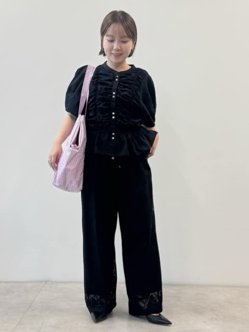 ブラック系のシャツ/ブラウス、ブラック系のその他パンツ、ピンク系のトートバッグを着用したレディースの春コーディネートの2枚目の写真