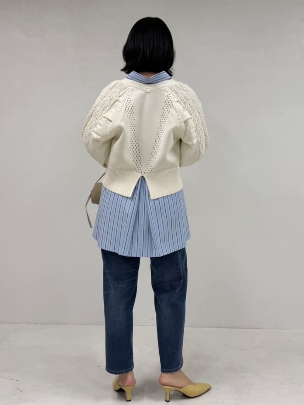 ブルー系のデニムパンツ、ホワイト系のカーディガン/ボレロ、ブルー系のシャツ/ブラウスを着用したレディースの冬コーディネートの2枚目の写真