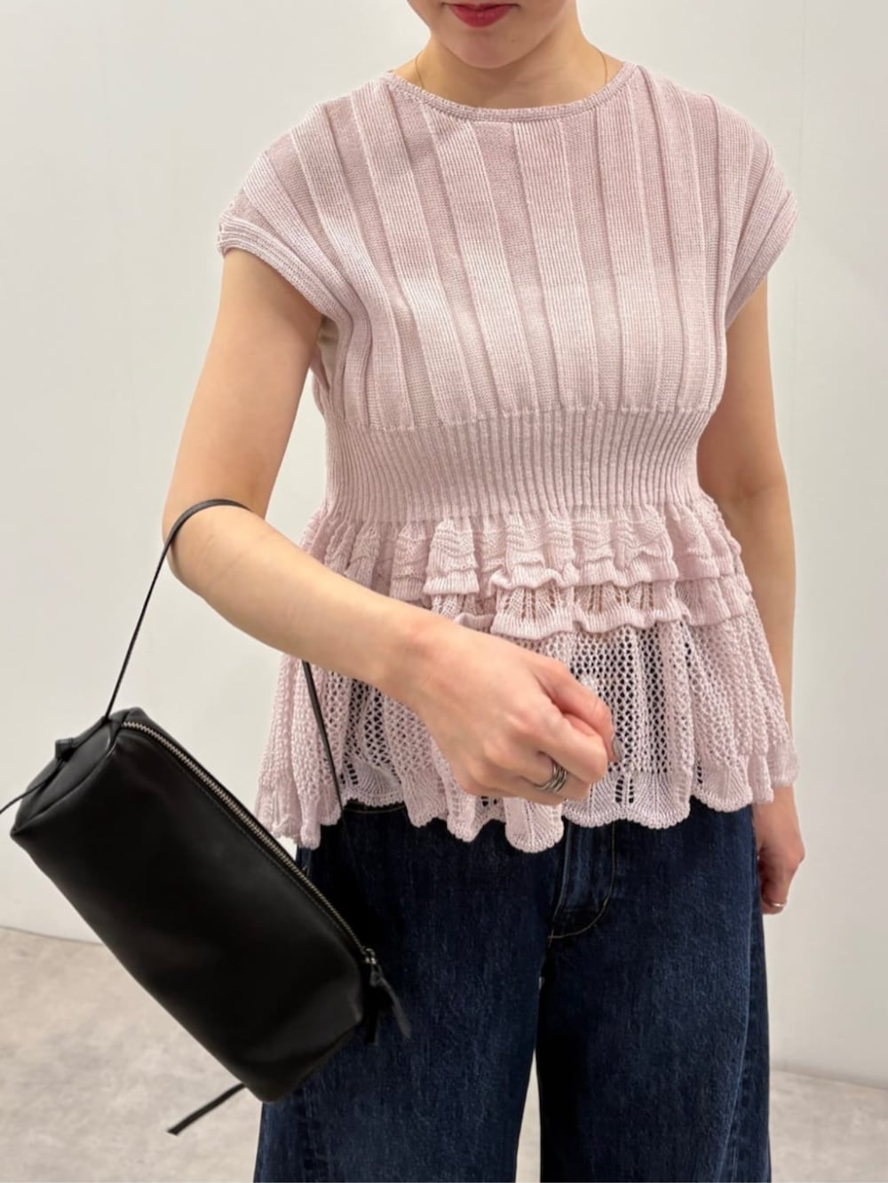 ブラック系のボストンバッグ、ブルー系のデニムパンツ、パープル系のニット/セーターを着用したレディースの春コーディネートの5枚目の写真