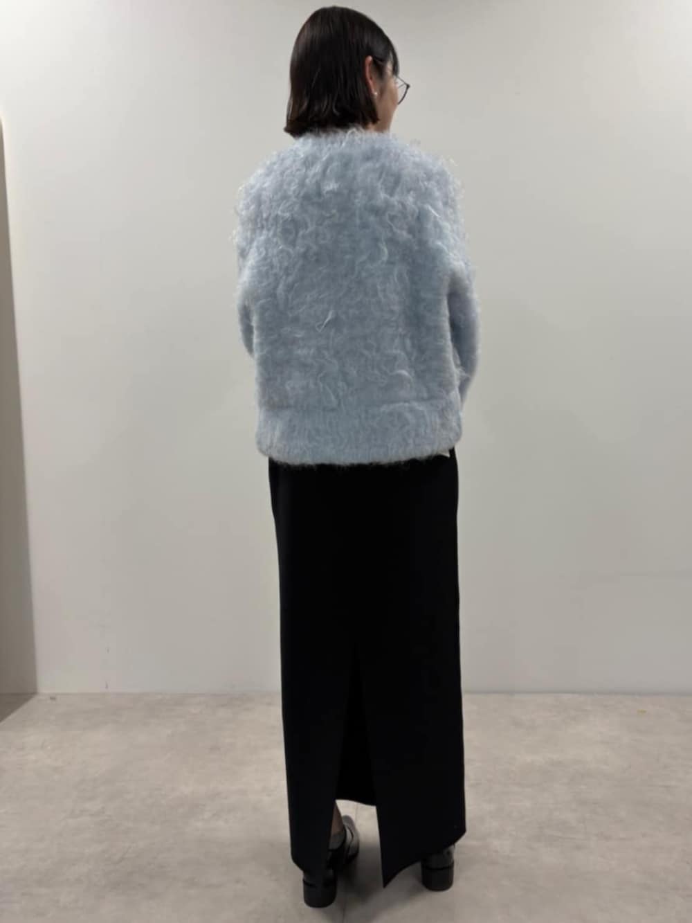 ブルー系のカーディガン/ボレロ、ブラック系のスカート、ブラック系のローファーを着用したレディースの秋コーディネートの3枚目の写真