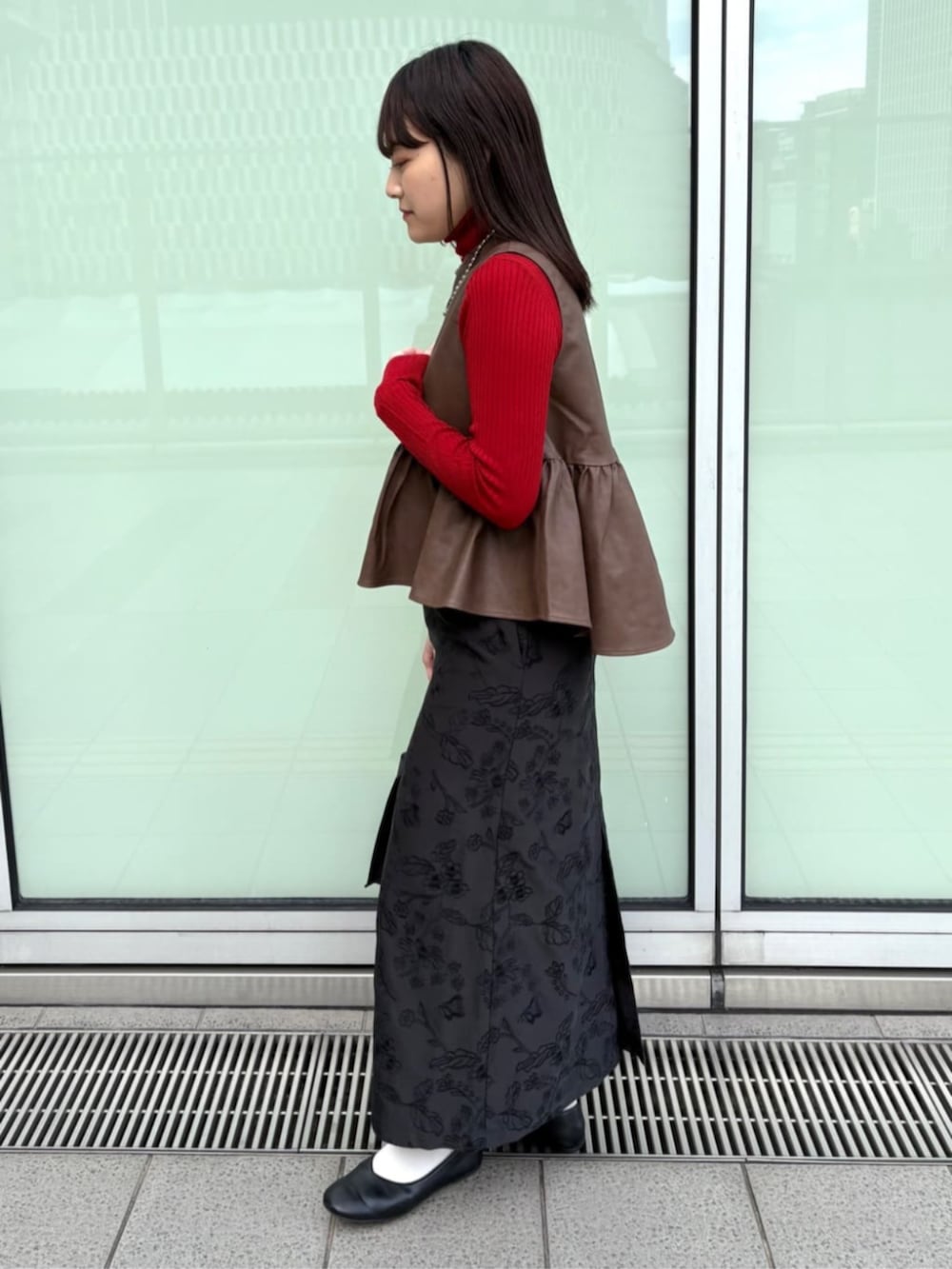 ブラウン系のベスト、ブラック系のスカートを着用したレディースの秋コーディネートの2枚目の写真