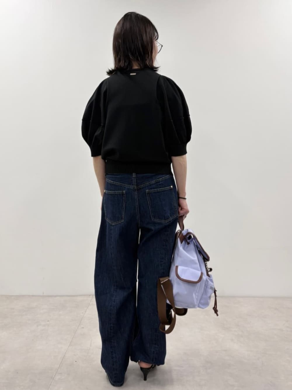 ブルー系のデニムパンツ、ブラック系のニット/セーター、パープル系のバックパック/リュックを着用したレディースの春コーディネートの2枚目の写真