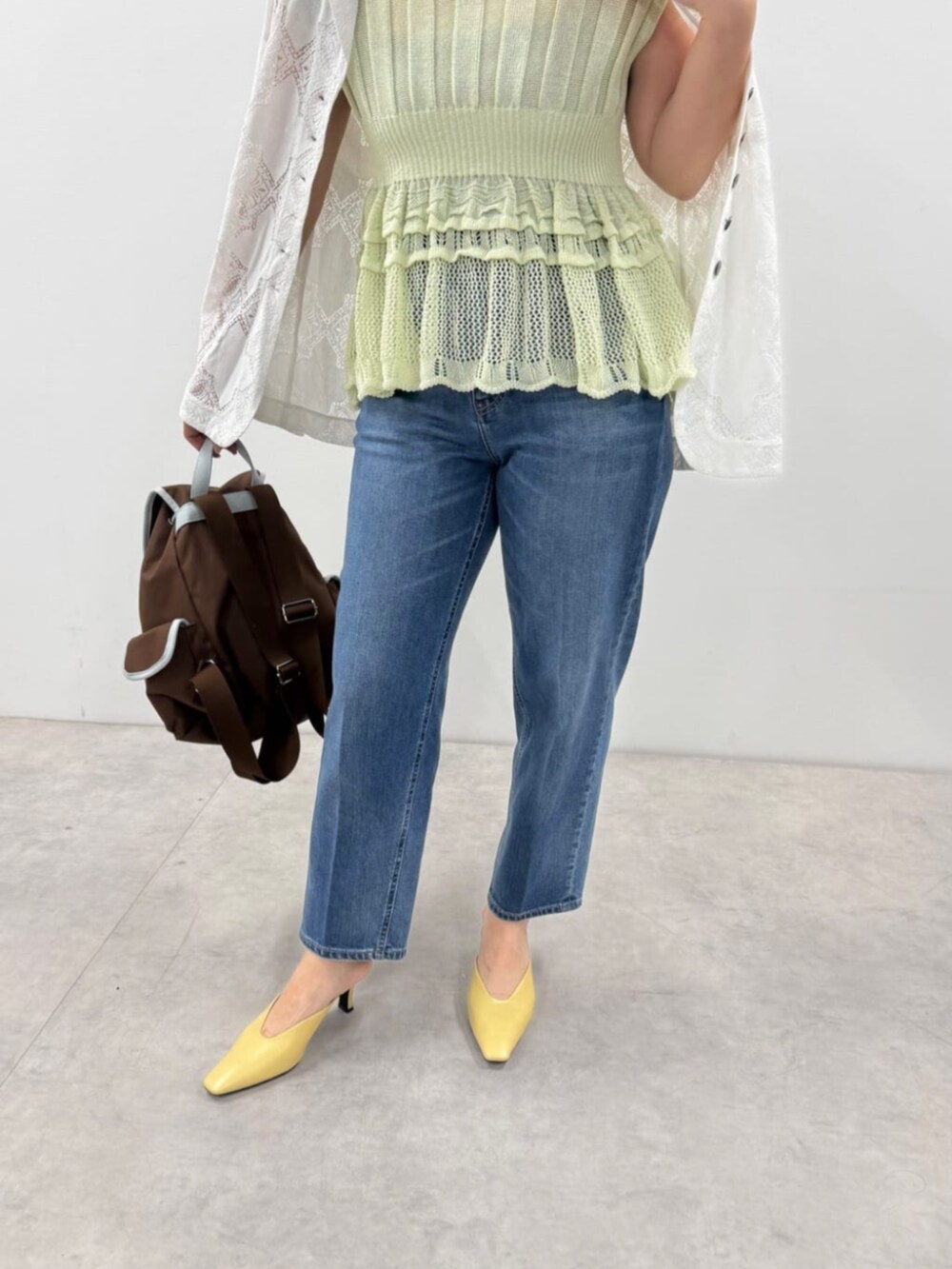 ブルー系のデニムパンツ、ブルー系のニット/セーター、ブラウン系のバックパック/リュックを着用したレディースの春コーディネートの3枚目の写真