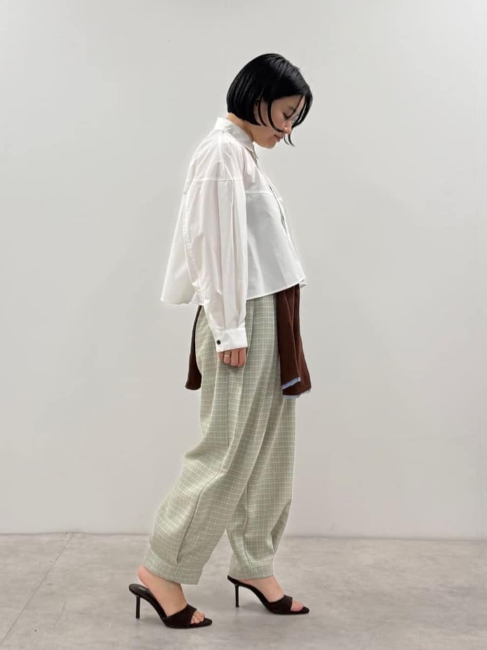 ブラウン系のカーディガン/ボレロ、ブルー系のその他パンツ、ホワイト系のシャツ/ブラウスを着用したレディースの春コーディネートの2枚目の写真