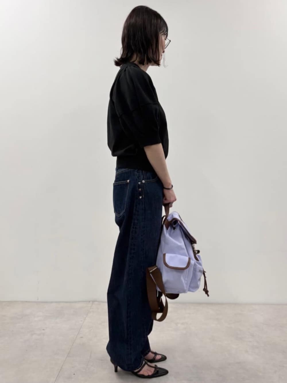 ブルー系のデニムパンツ、ブラック系のニット/セーター、パープル系のバックパック/リュックを着用したレディースの春コーディネートの3枚目の写真