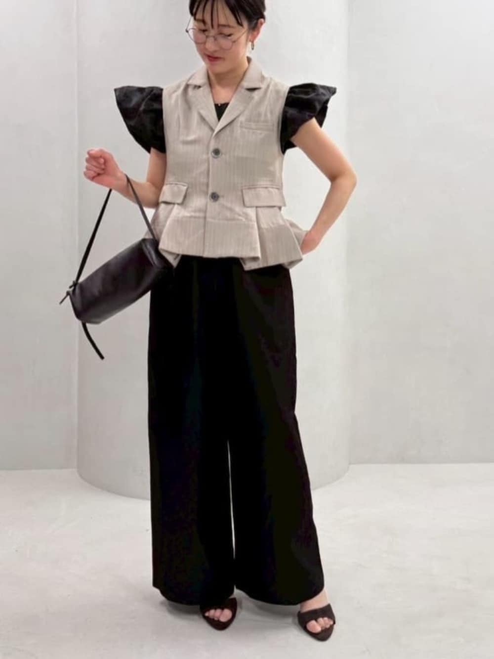 ブラック系のボストンバッグ、ブラック系のつなぎ/オールインワン、ベージュ系のベストを着用したレディースの冬コーディネートの4枚目の写真