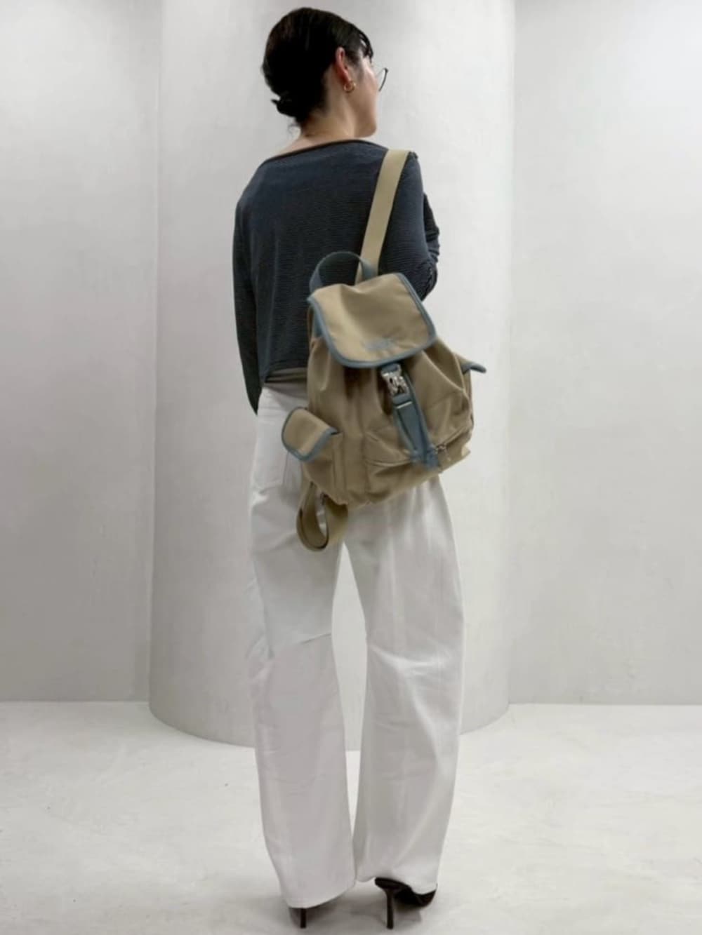 ベージュ系のバックパック/リュック、ホワイト系のデニムパンツ、ブルー系のカーディガン/ボレロを着用したレディースの春コーディネートの3枚目の写真