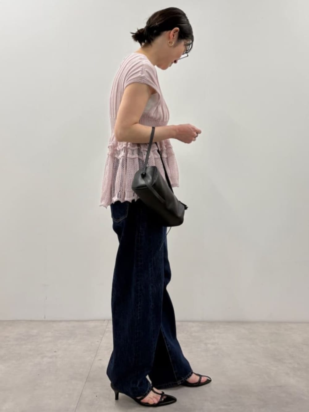 ブラック系のボストンバッグ、ブルー系のデニムパンツ、パープル系のニット/セーターを着用したレディースの春コーディネートの3枚目の写真