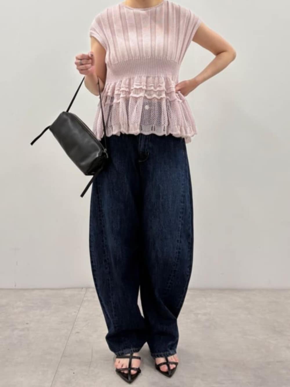 ブラック系のボストンバッグ、ブルー系のデニムパンツ、パープル系のニット/セーターを着用したレディースの春コーディネートの4枚目の写真