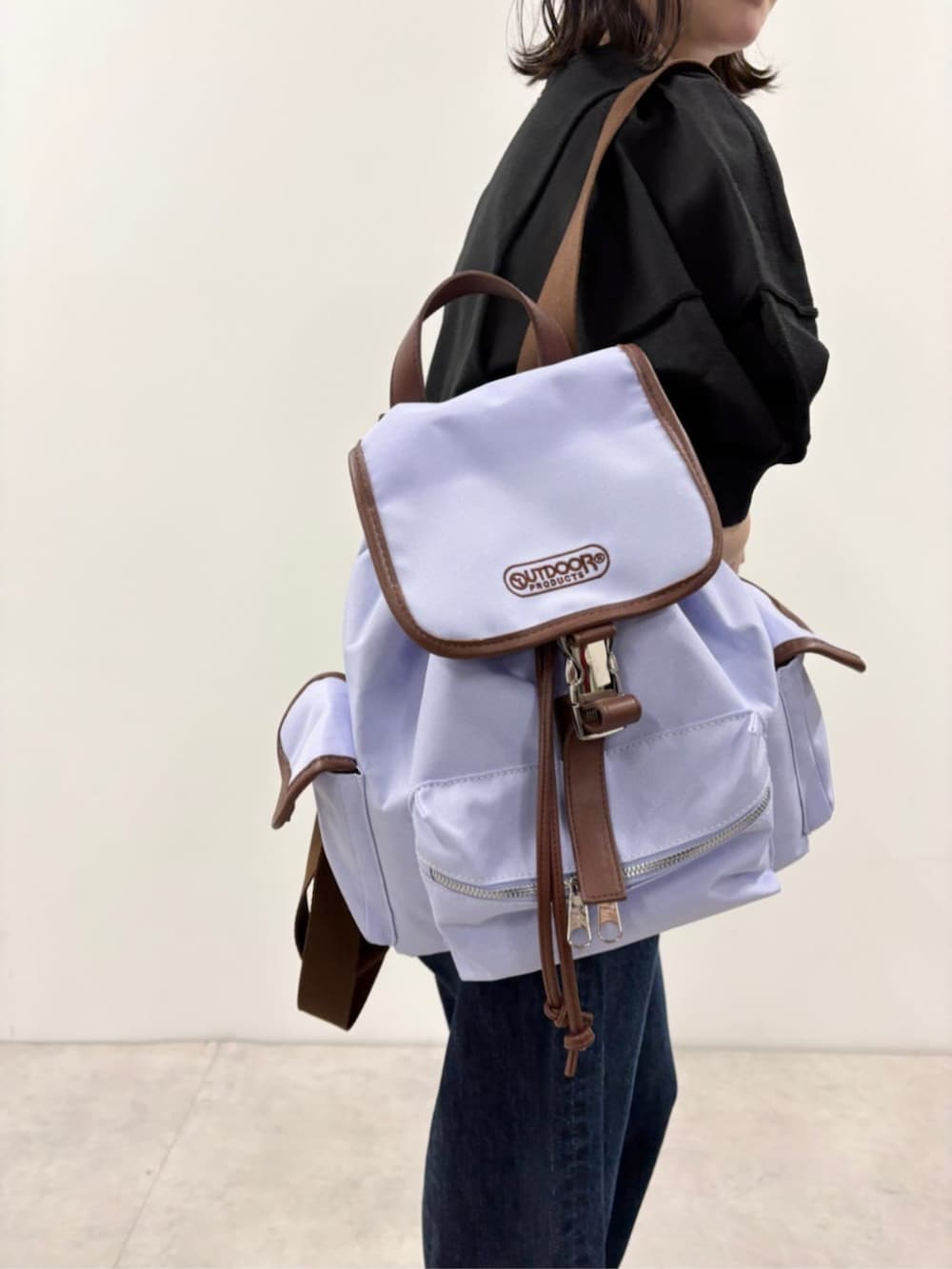 ブルー系のデニムパンツ、ブラック系のニット/セーター、パープル系のバックパック/リュックを着用したレディースの春コーディネートの6枚目の写真