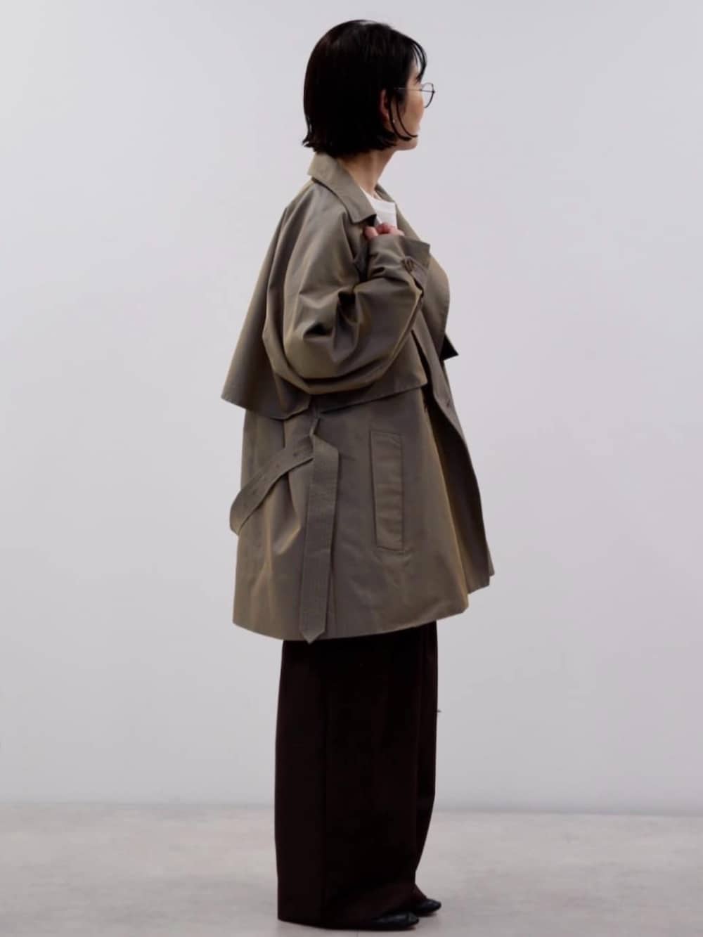 ブラウン系のスラックス、ブルー系のトレンチコート、その他のトートバッグを着用したレディースの秋コーディネートの2枚目の写真