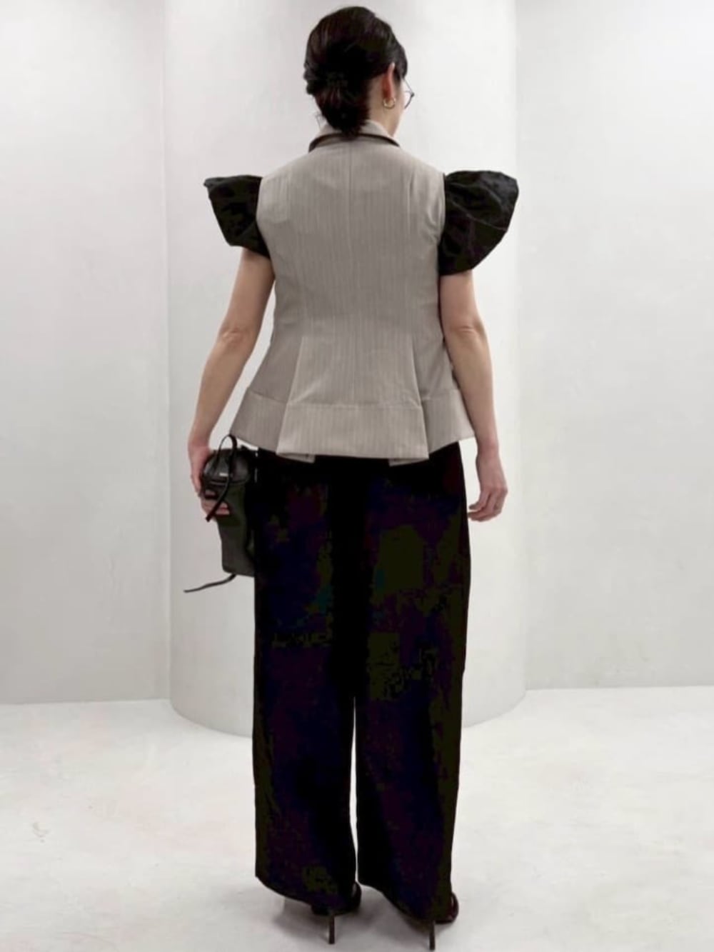 ブラック系のボストンバッグ、ブラック系のつなぎ/オールインワン、ベージュ系のベストを着用したレディースの冬コーディネートの3枚目の写真