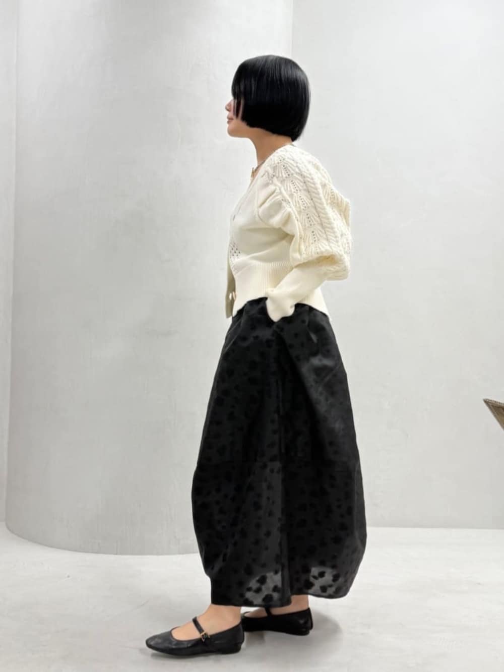 ホワイト系のカーディガン/ボレロ、ベージュ系のボストンバッグ、ブラック系のスカートを着用したレディースの冬コーディネートの3枚目の写真