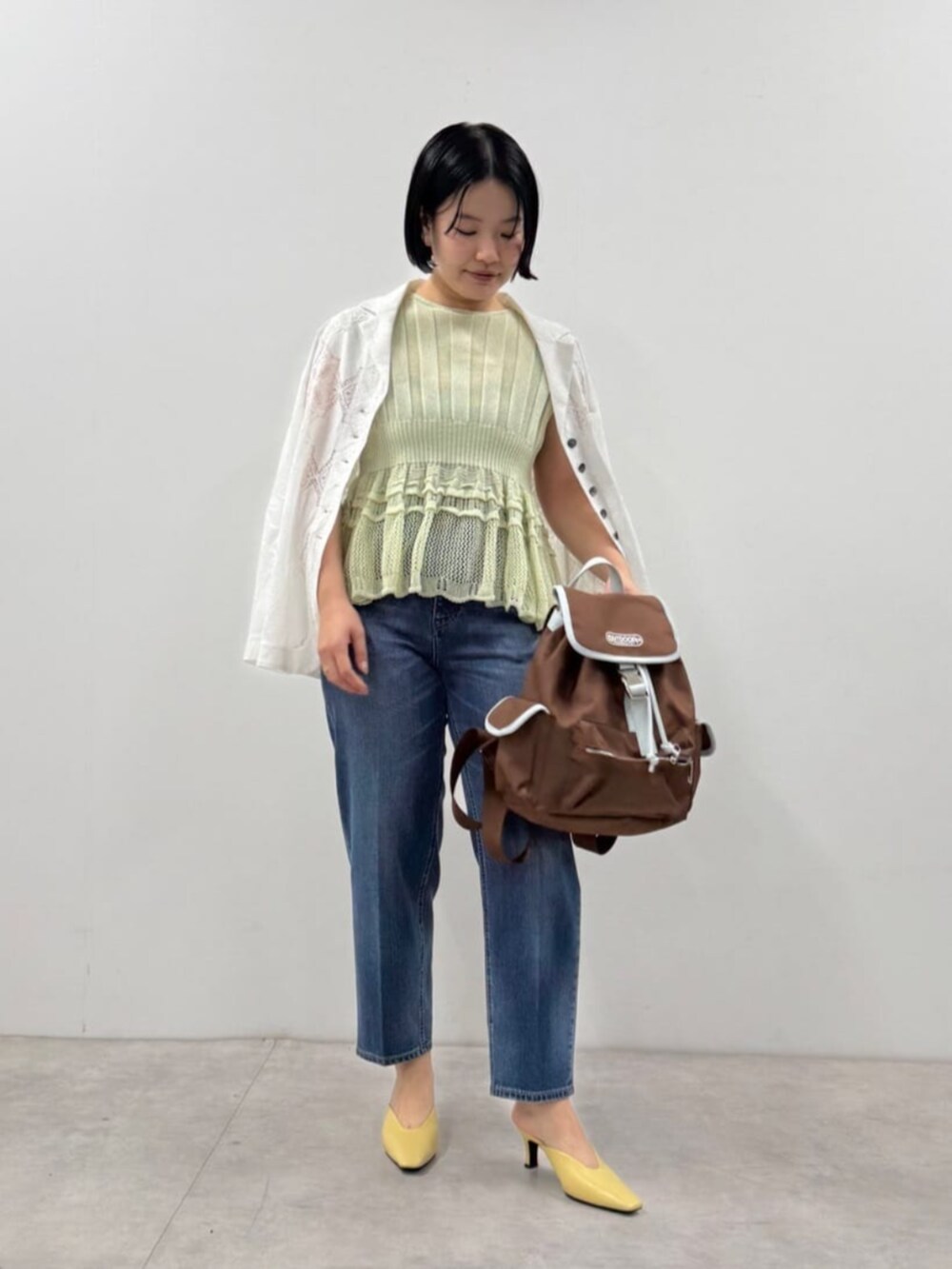 ブルー系のデニムパンツ、ブルー系のニット/セーター、ブラウン系のバックパック/リュックを着用したレディースの春コーディネートの2枚目の写真