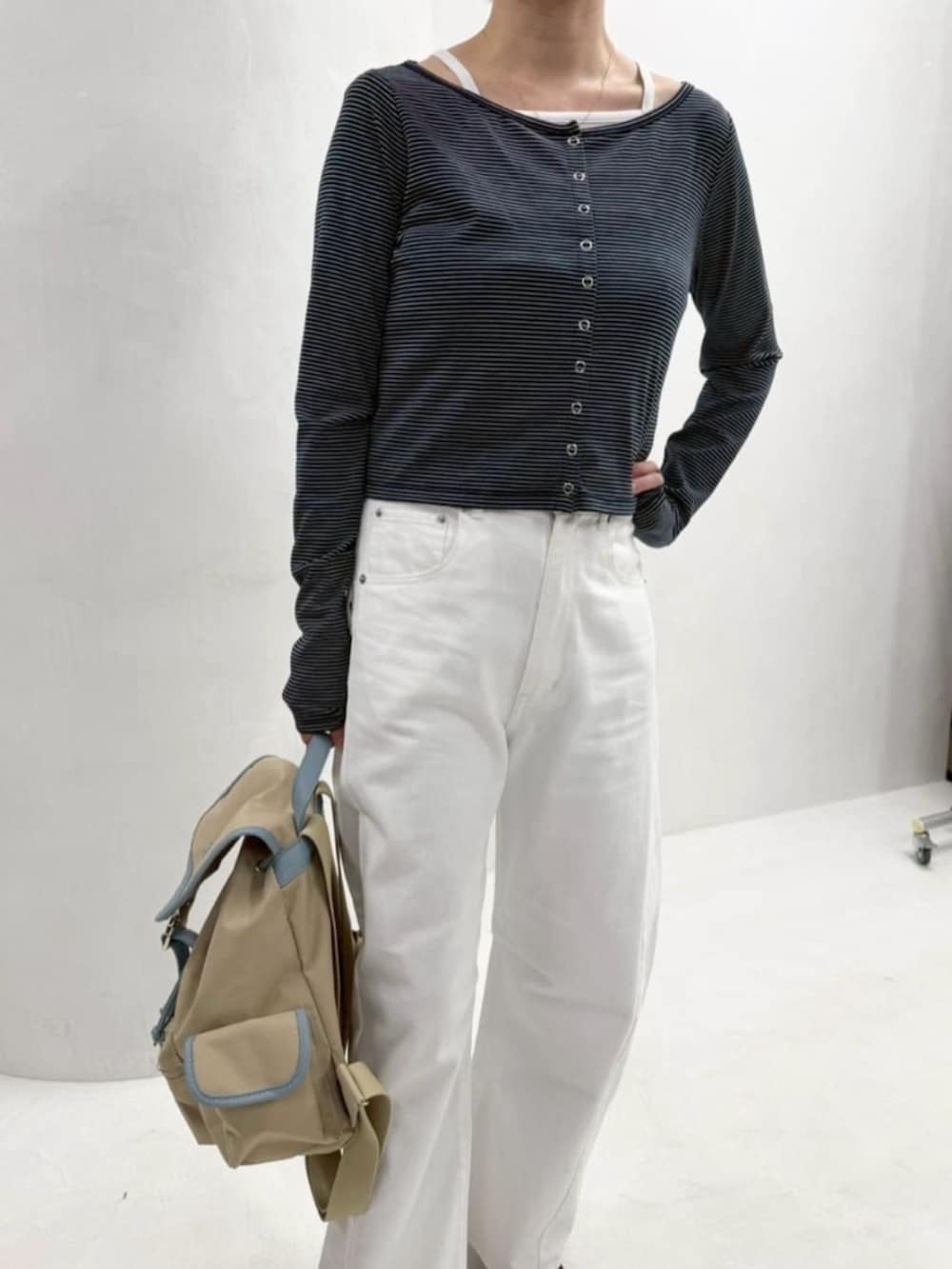 ベージュ系のバックパック/リュック、ホワイト系のデニムパンツ、ブルー系のカーディガン/ボレロを着用したレディースの春コーディネートの6枚目の写真