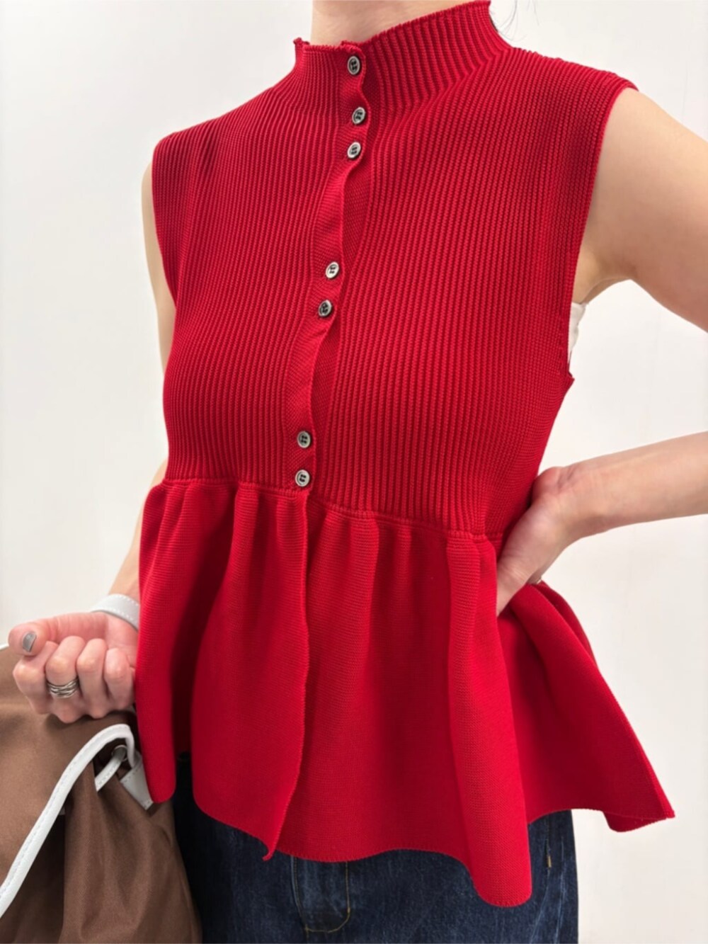 ブルー系のデニムパンツ、ブラウン系のバックパック/リュック、レッド系のベストを着用したレディースの春コーディネートの5枚目の写真