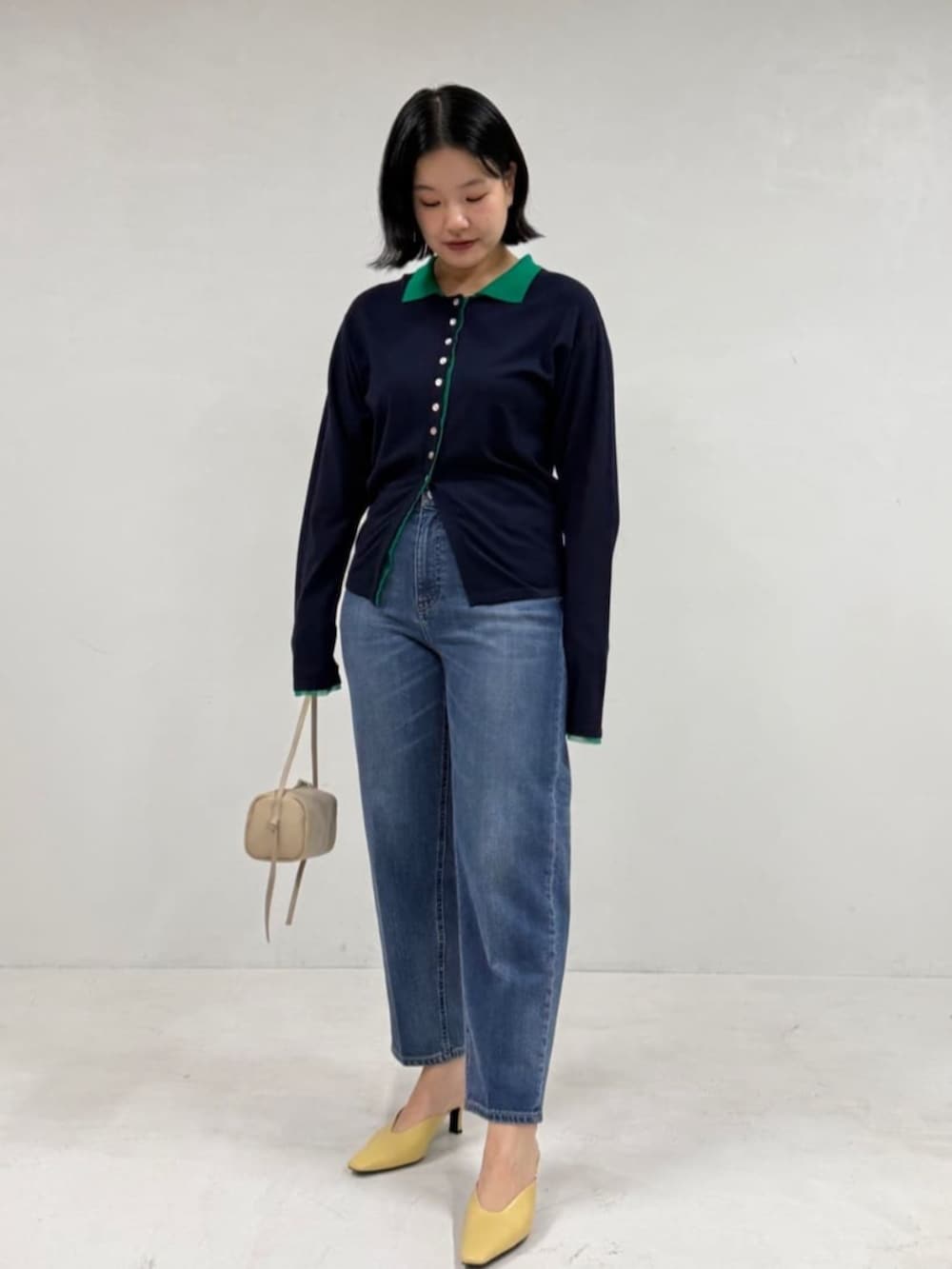 ブルー系のデニムパンツ、ベージュ系のボストンバッグ、ブルー系のカーディガン/ボレロを着用したレディースの冬コーディネートの2枚目の写真