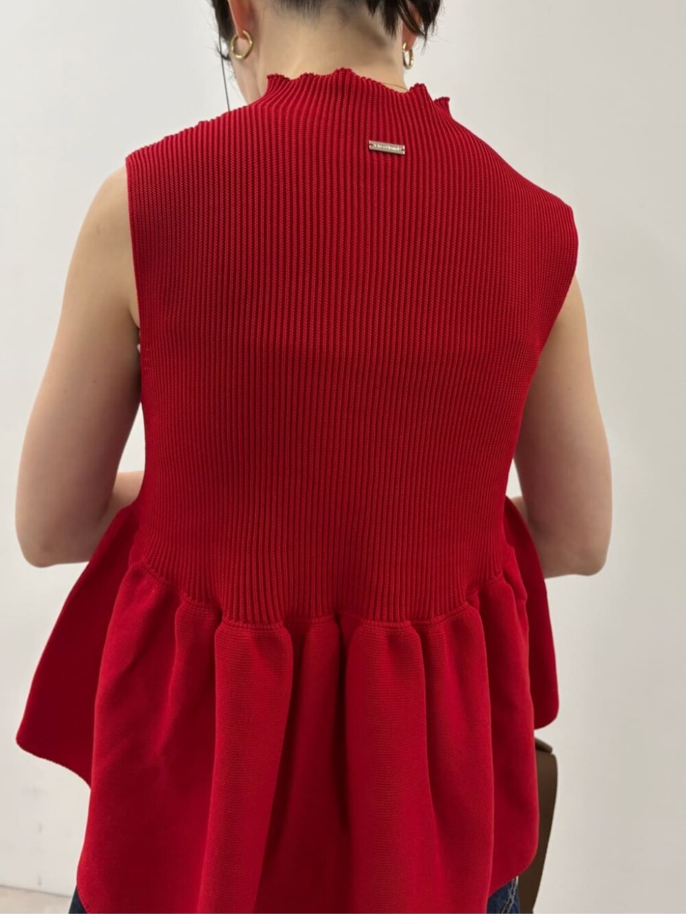 ブルー系のデニムパンツ、ブラウン系のバックパック/リュック、レッド系のベストを着用したレディースの春コーディネートの6枚目の写真