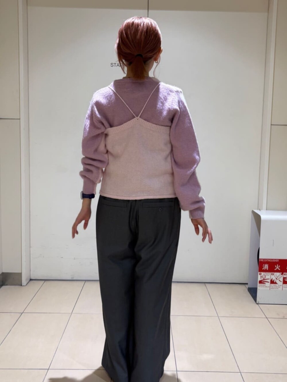 ピンク系のニット/セーター、ピンク系のチューブトップ、グレー系のスラックスを着用したレディースの冬コーディネートの3枚目の写真