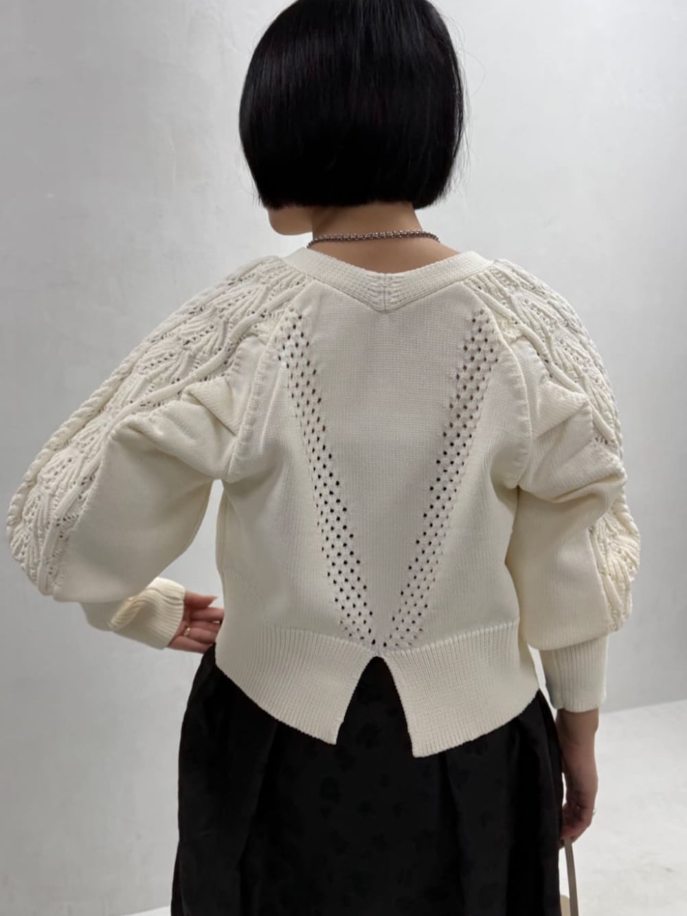 ホワイト系のカーディガン/ボレロ、ベージュ系のボストンバッグ、ブラック系のスカートを着用したレディースの冬コーディネートの4枚目の写真