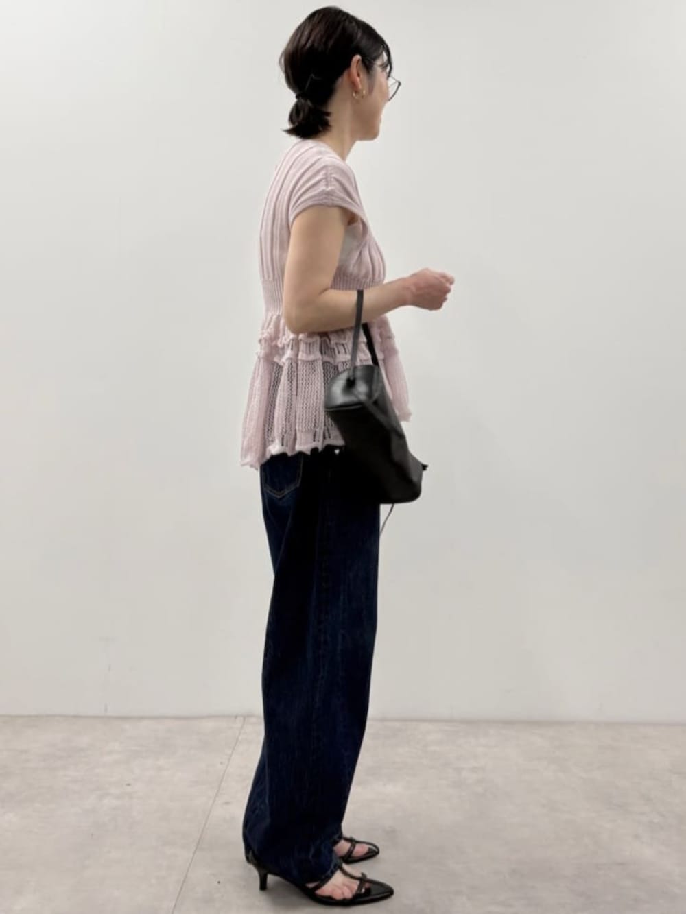 ブラック系のボストンバッグ、ブルー系のデニムパンツ、パープル系のニット/セーターを着用したレディースの春コーディネートの2枚目の写真