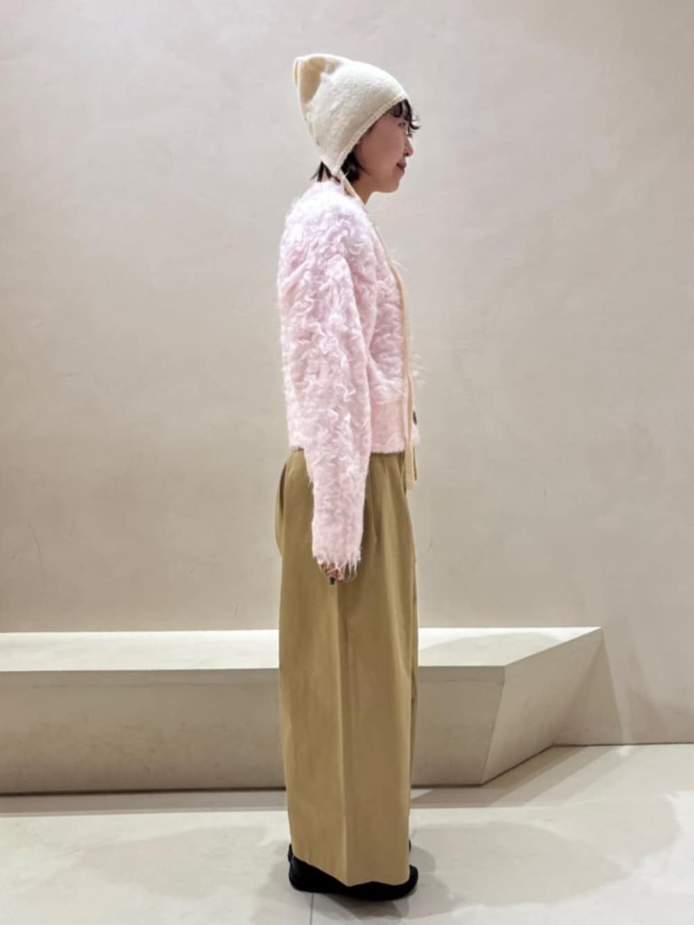 イエロー系のチノパンツ、ピンク系のカーディガン/ボレロ、ホワイト系のニットキャップ/ビーニーを着用したレディースの秋コーディネートの2枚目の写真