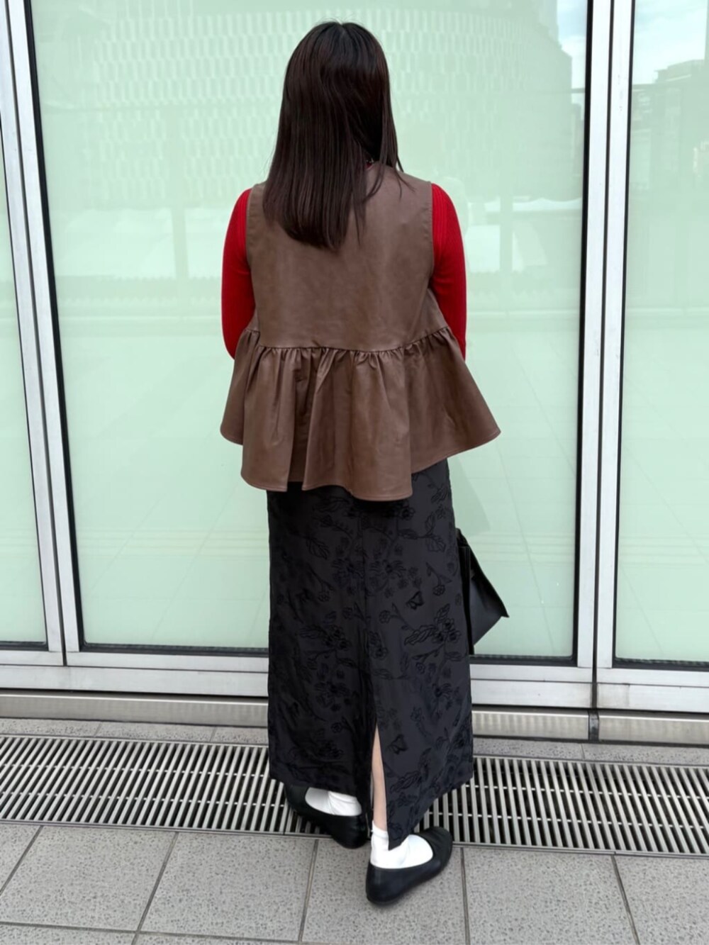 ブラウン系のベスト、ブラック系のスカートを着用したレディースの秋コーディネートの3枚目の写真