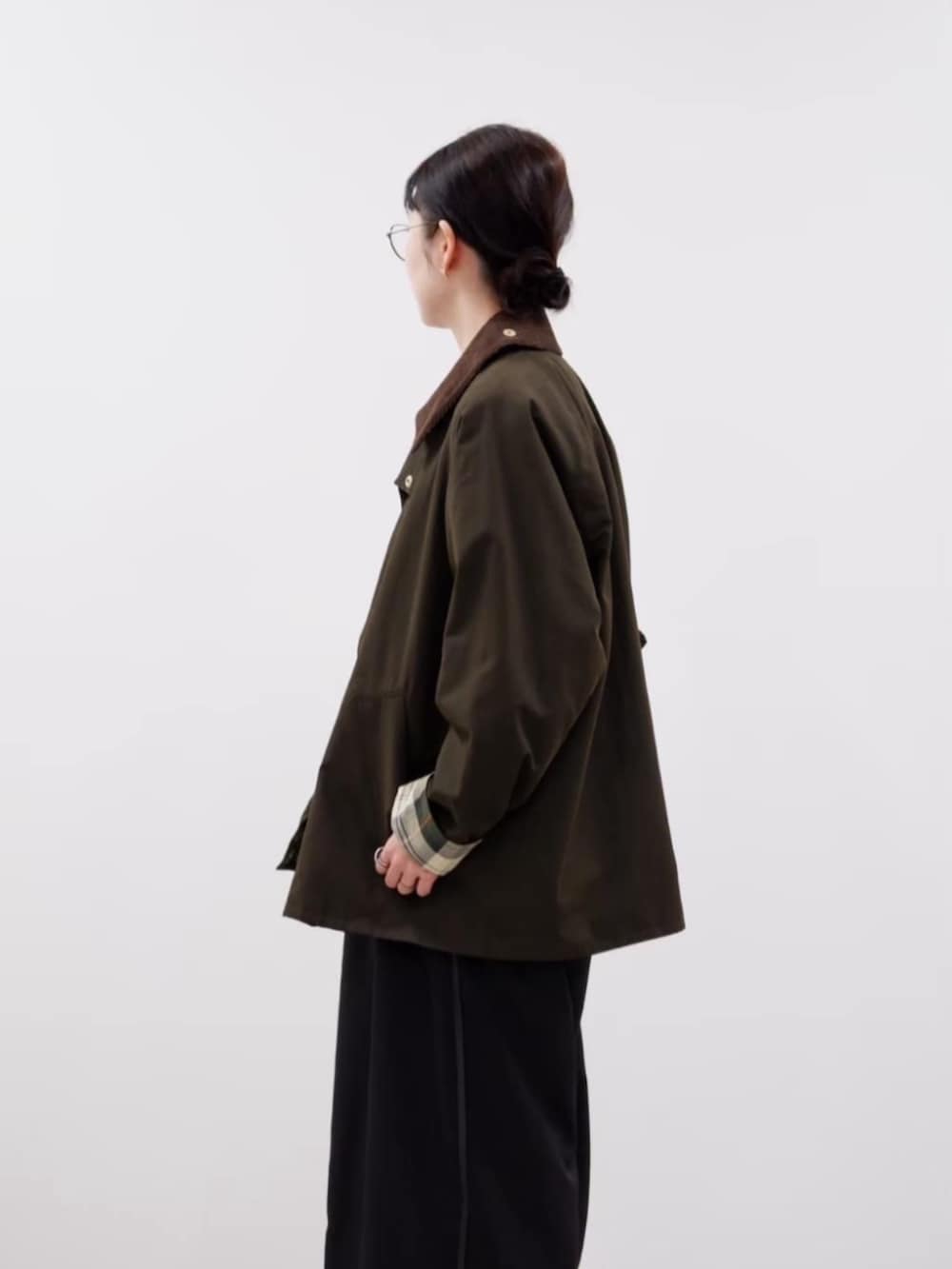 グリーン系のブルゾン、ブラウン系のベスト、ブラック系のスラックスを着用したレディースの秋コーディネートの2枚目の写真