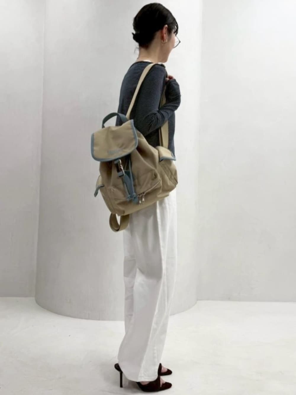 ベージュ系のバックパック/リュック、ホワイト系のデニムパンツ、ブルー系のカーディガン/ボレロを着用したレディースの春コーディネートの5枚目の写真