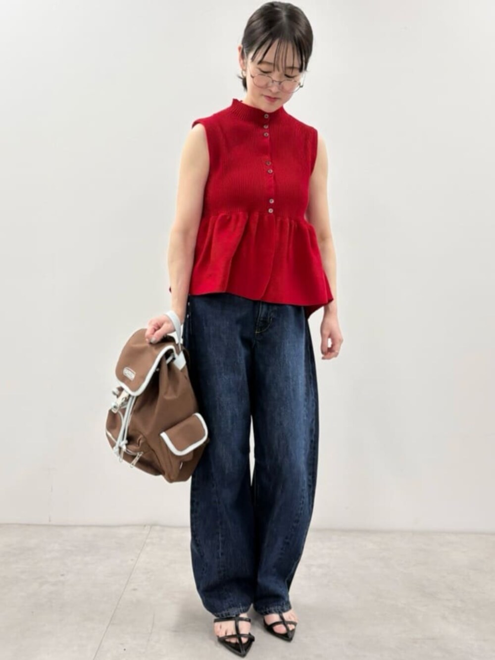 ブルー系のデニムパンツ、ブラウン系のバックパック/リュック、レッド系のベストを着用したレディースの春コーディネートの4枚目の写真