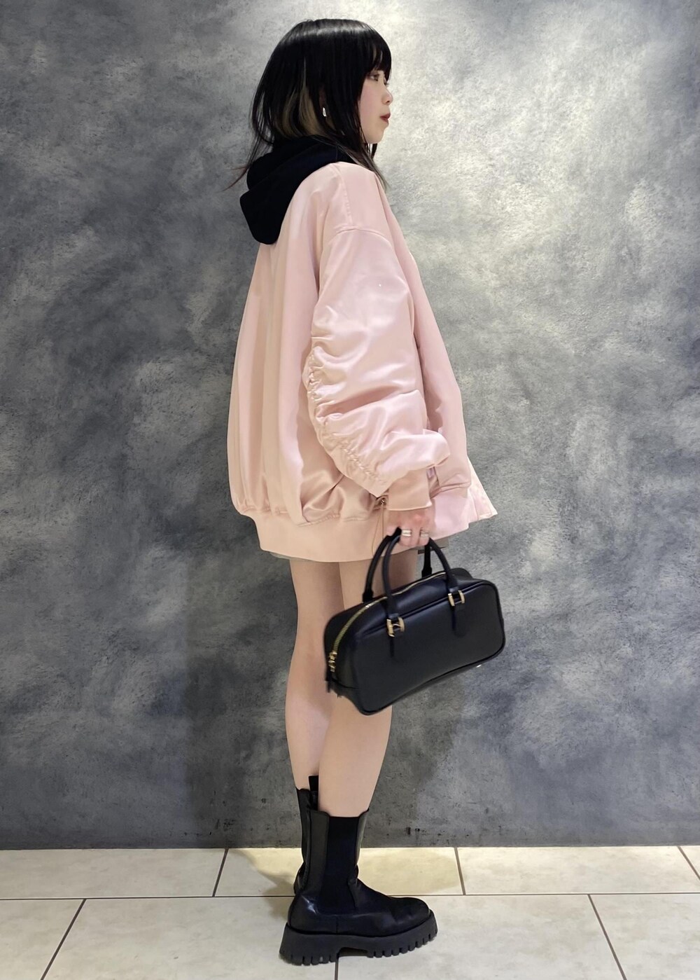 ピンク系のブルゾン、ブラック系のボストンバッグ、グレー系のスラックスを着用したレディースの冬コーディネートの2枚目の写真