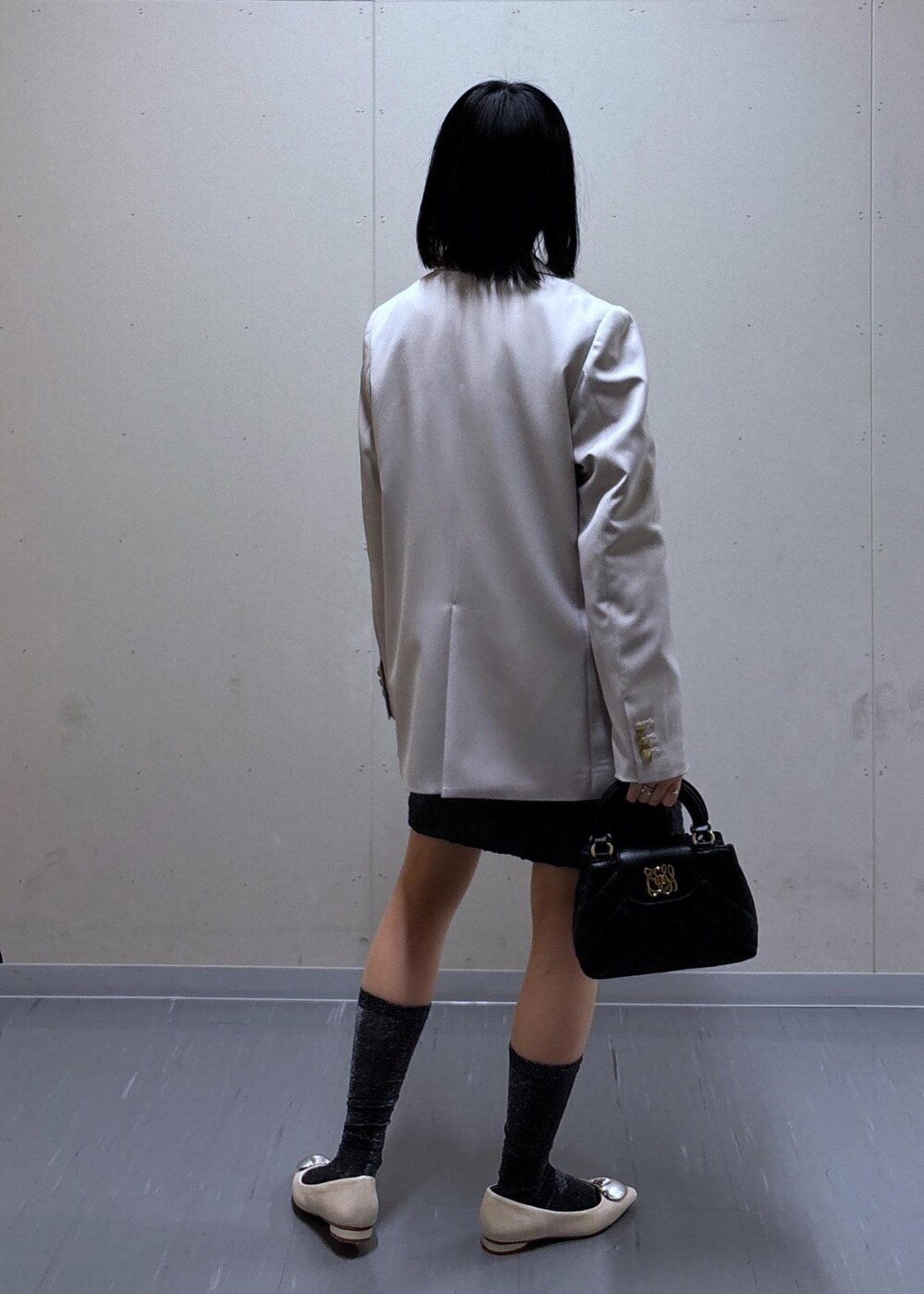 グレー系のスカート、ベージュ系のテーラードジャケット、ホワイト系のバレエシューズを着用したレディースの春コーディネートの3枚目の写真