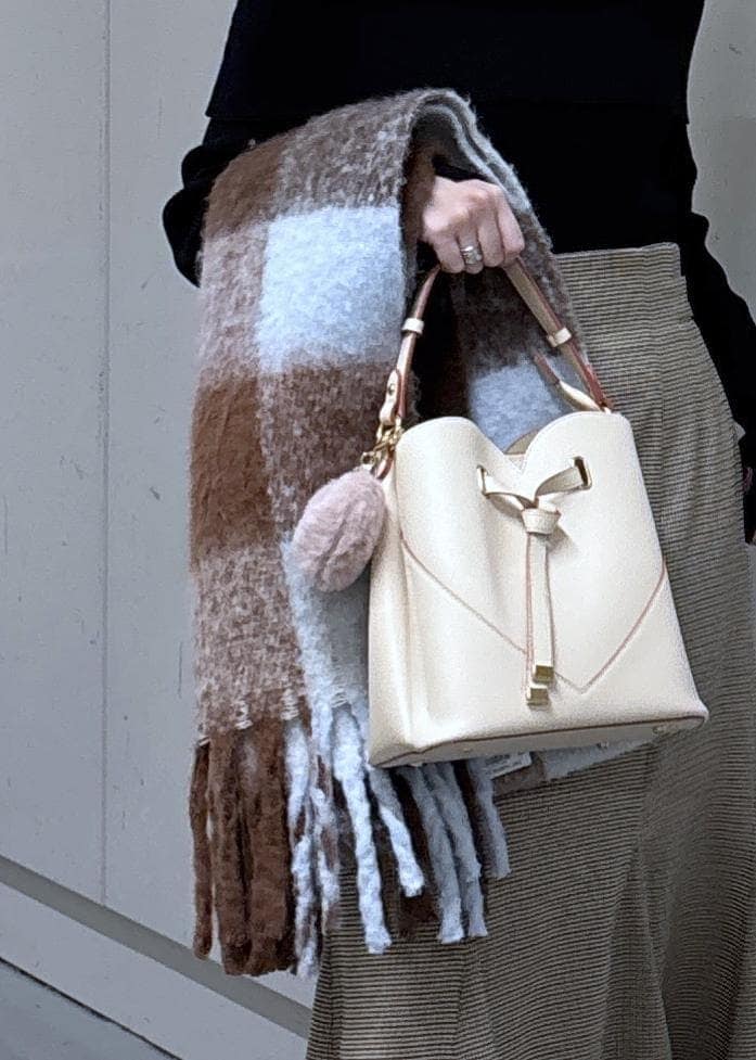 ベージュ系のショルダーバッグ、ベージュ系のスカート、ブラック系のニット/セーターを着用したレディースの冬コーディネートの8枚目の写真