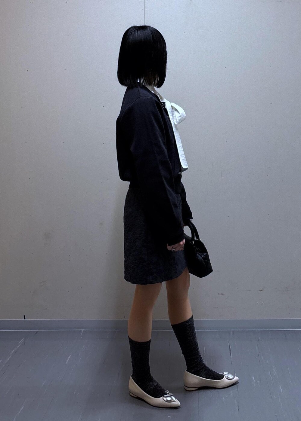 グレー系のスカート、ベージュ系のテーラードジャケット、ホワイト系のバレエシューズを着用したレディースの春コーディネートの7枚目の写真