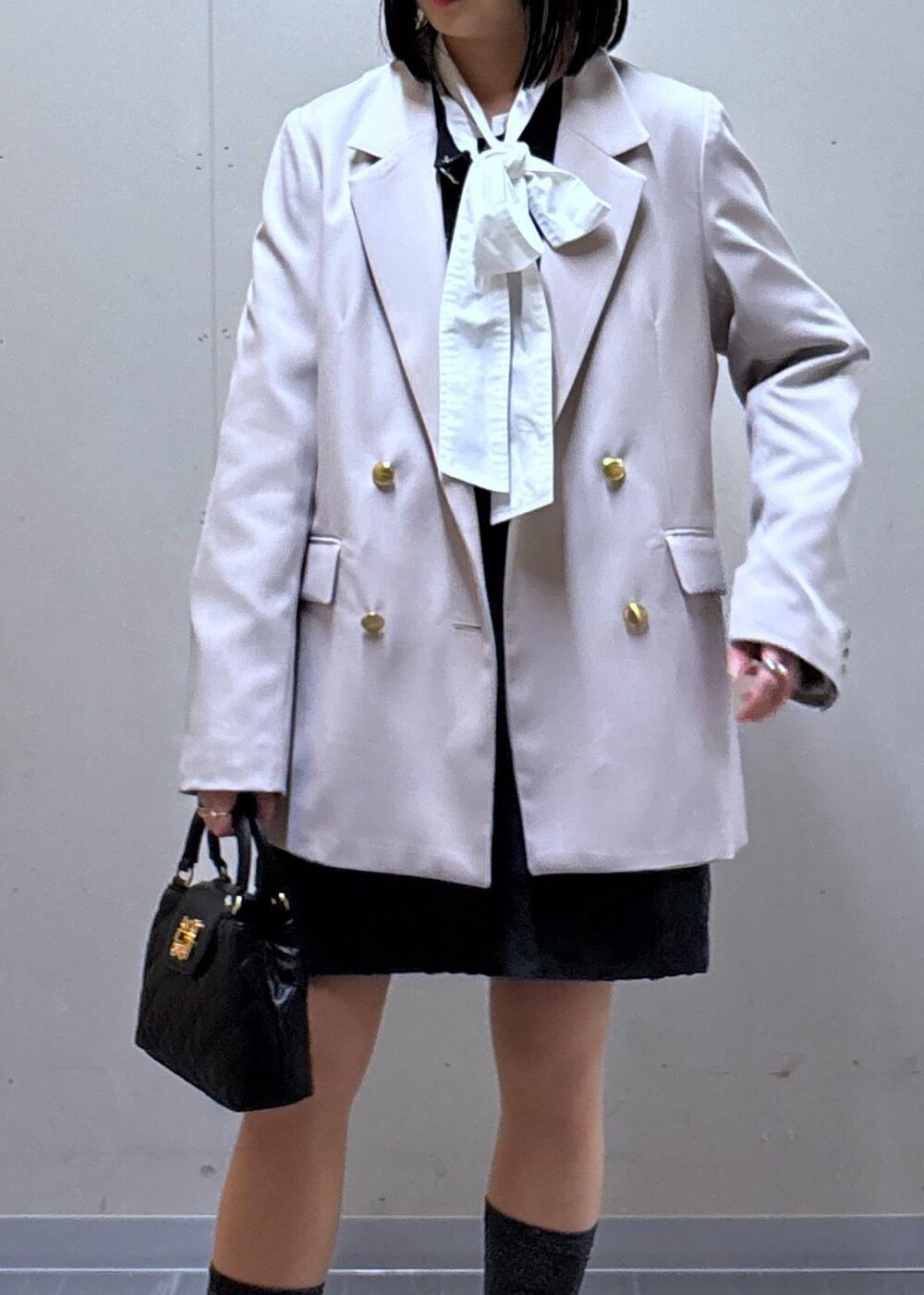 グレー系のスカート、ベージュ系のテーラードジャケット、ホワイト系のバレエシューズを着用したレディースの春コーディネートの5枚目の写真