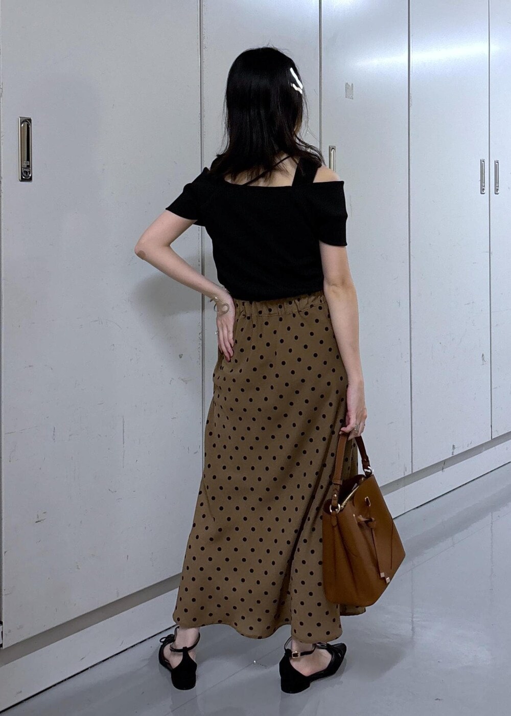 ブラウン系のショルダーバッグ、ブラウン系のスカート、ブラック系のニット/セーターを着用したレディースの夏コーディネートの3枚目の写真