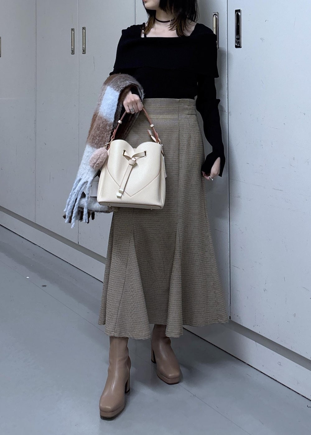 ベージュ系のショルダーバッグ、ベージュ系のスカート、ブラック系のニット/セーターを着用したレディースの冬コーディネートの4枚目の写真