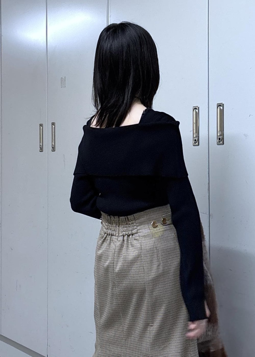 ベージュ系のショルダーバッグ、ベージュ系のスカート、ブラック系のニット/セーターを着用したレディースの冬コーディネートの9枚目の写真