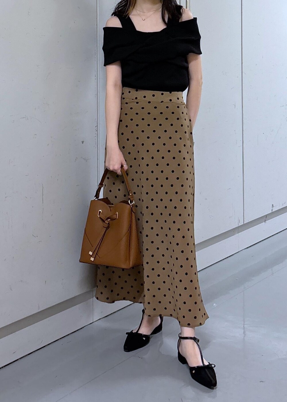 ブラウン系のショルダーバッグ、ブラウン系のスカート、ブラック系のニット/セーターを着用したレディースの夏コーディネートの4枚目の写真