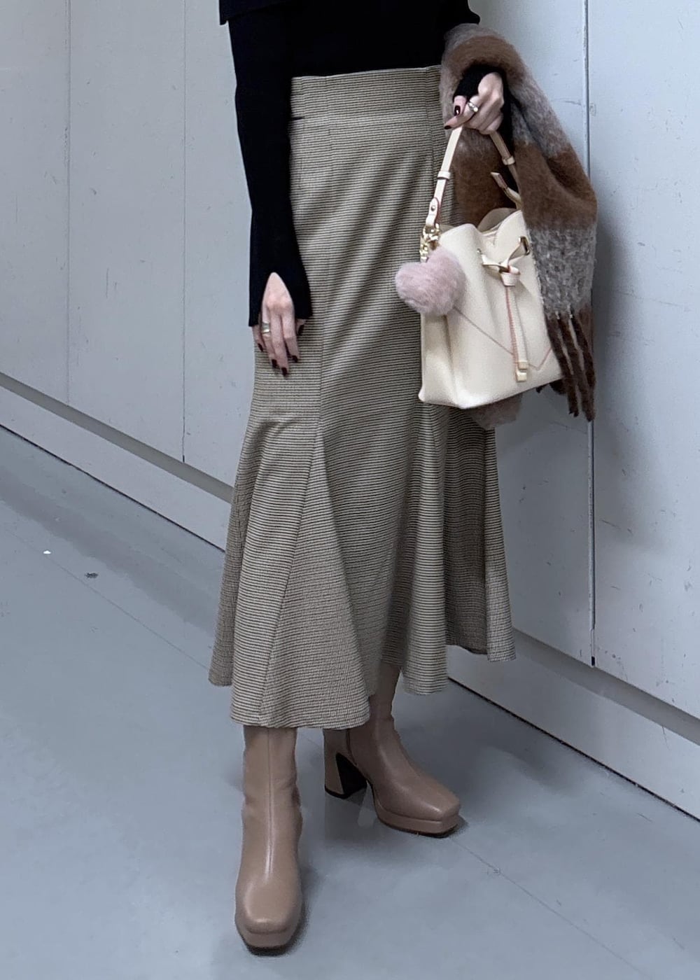 ベージュ系のショルダーバッグ、ベージュ系のスカート、ブラック系のニット/セーターを着用したレディースの冬コーディネートの10枚目の写真