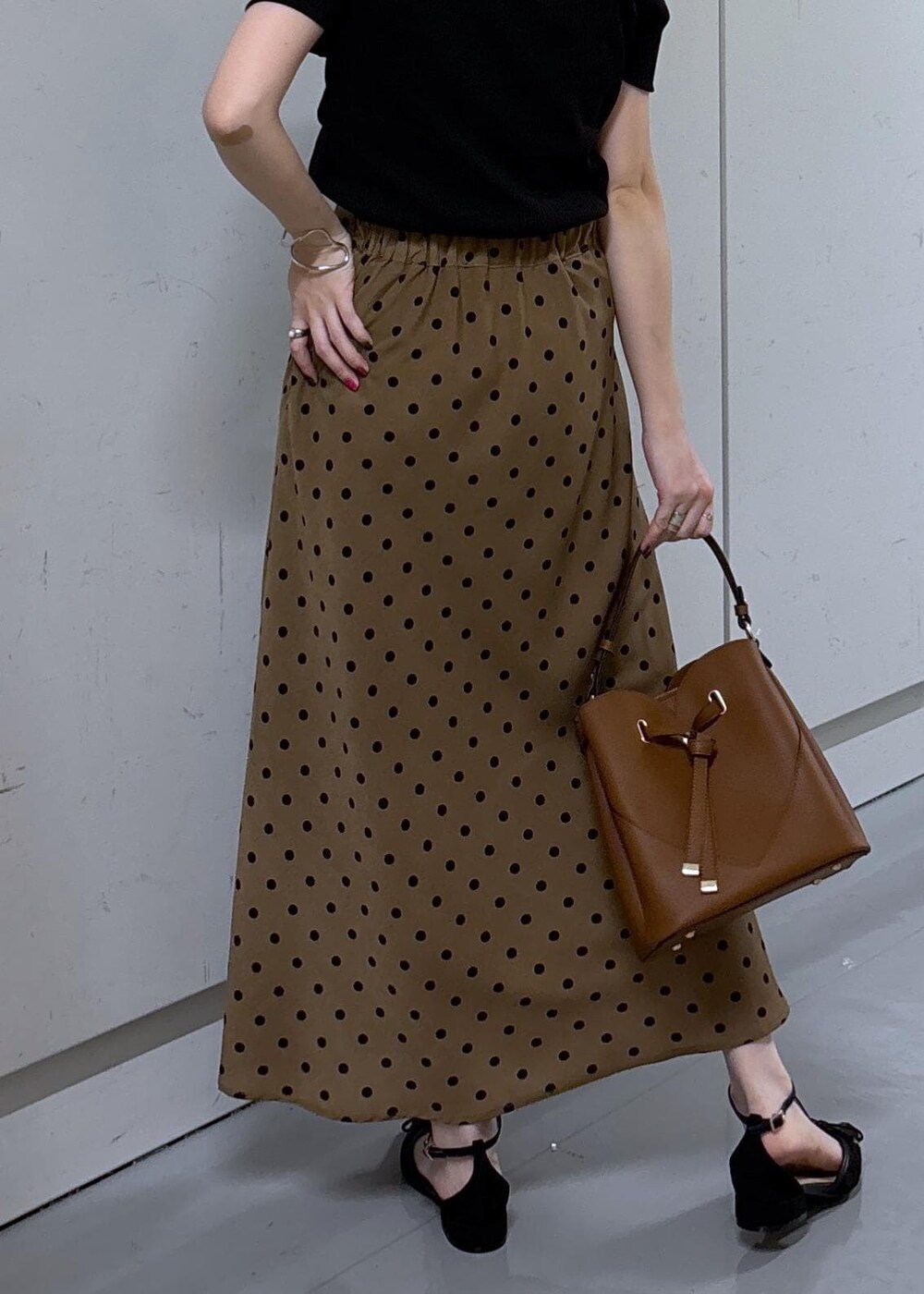 ブラウン系のショルダーバッグ、ブラウン系のスカート、ブラック系のニット/セーターを着用したレディースの夏コーディネートの6枚目の写真