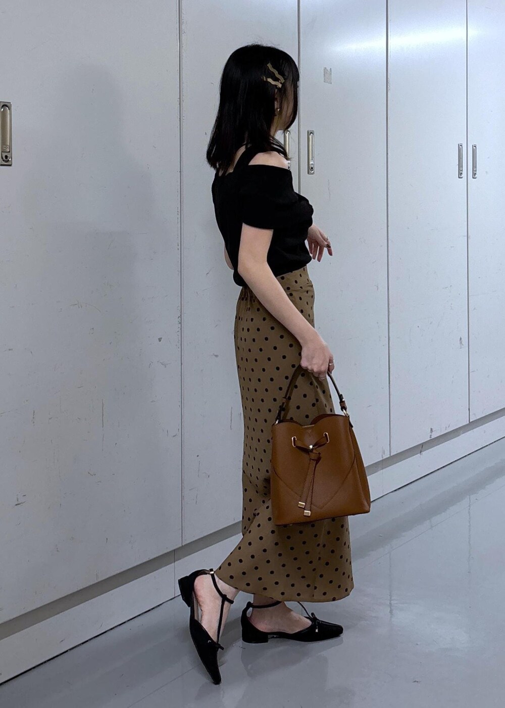 ブラウン系のショルダーバッグ、ブラウン系のスカート、ブラック系のニット/セーターを着用したレディースの夏コーディネートの2枚目の写真