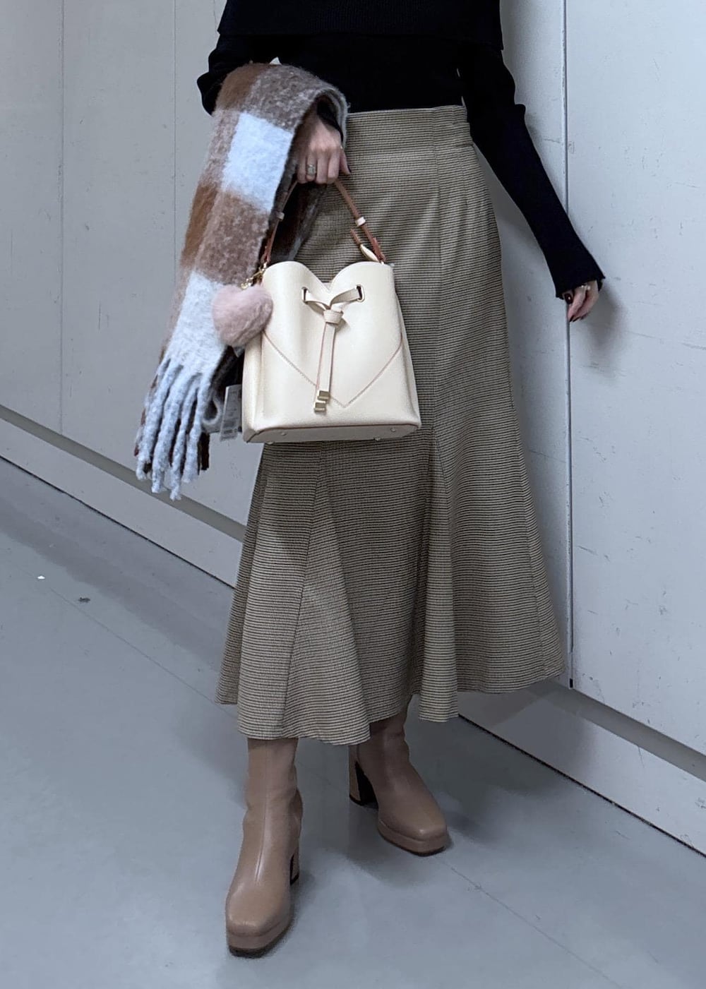 ベージュ系のショルダーバッグ、ベージュ系のスカート、ブラック系のニット/セーターを着用したレディースの冬コーディネートの7枚目の写真
