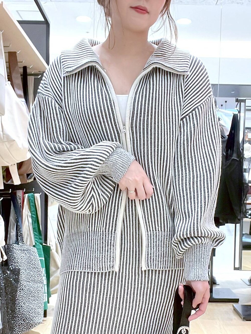 ホワイト系のタンクトップ、ブラック系のハンドバッグ、ベージュ系のスカートを着用したレディースの秋コーディネートの7枚目の写真