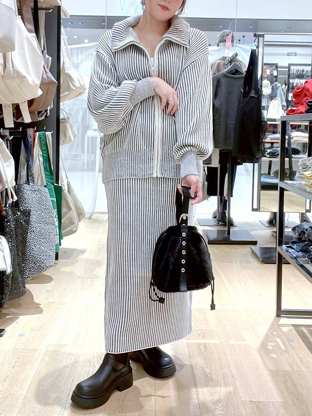 ホワイト系のタンクトップ、ブラック系のハンドバッグ、ベージュ系のスカートを着用したレディースの秋コーディネートの2枚目の写真