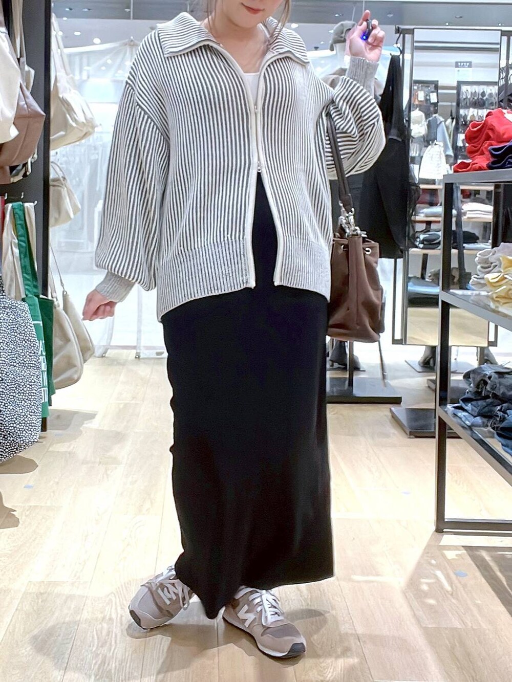 ブラウン系のスニーカー、ブラウン系のショルダーバッグ、ベージュ系のニット/セーターを着用したレディースの秋コーディネートの2枚目の写真