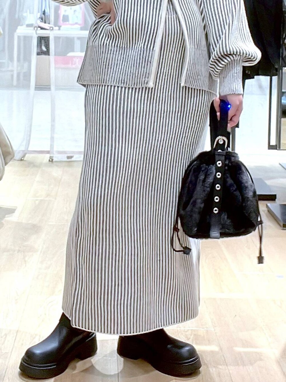 ホワイト系のタンクトップ、ブラック系のハンドバッグ、ベージュ系のスカートを着用したレディースの秋コーディネートの8枚目の写真