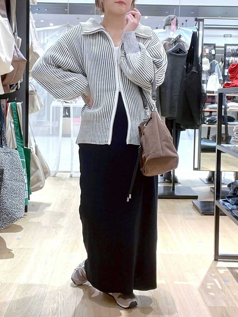 ブラウン系のスニーカー、ブラウン系のショルダーバッグ、ベージュ系のニット/セーターを着用したレディースの秋コーディネートの3枚目の写真